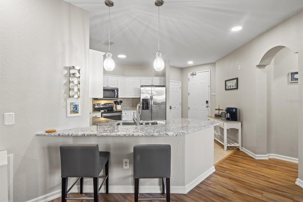 301 Terrace Ridge Circle, Unit 301 Davenport, FL 33896 - Photo 5 of 35 a kitchen with kitchen island granite countertop a sink cabinets and stainless steel appliances
