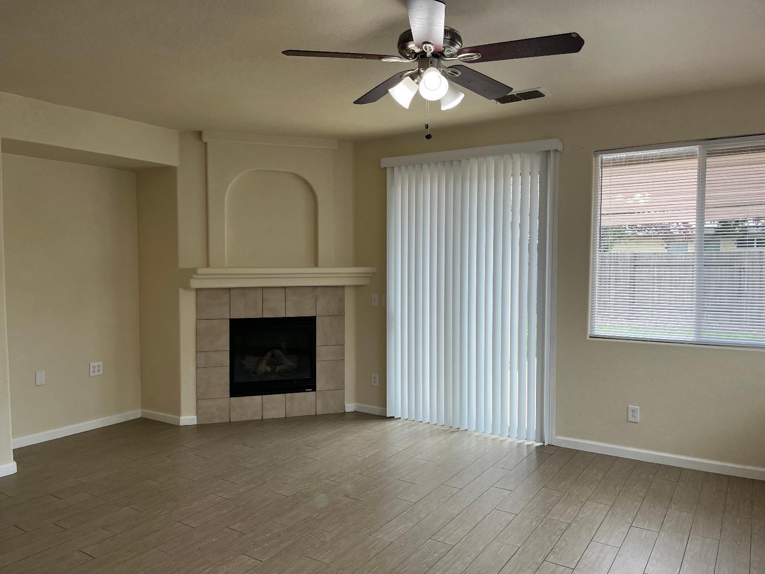 an empty room with fireplace fan and windows