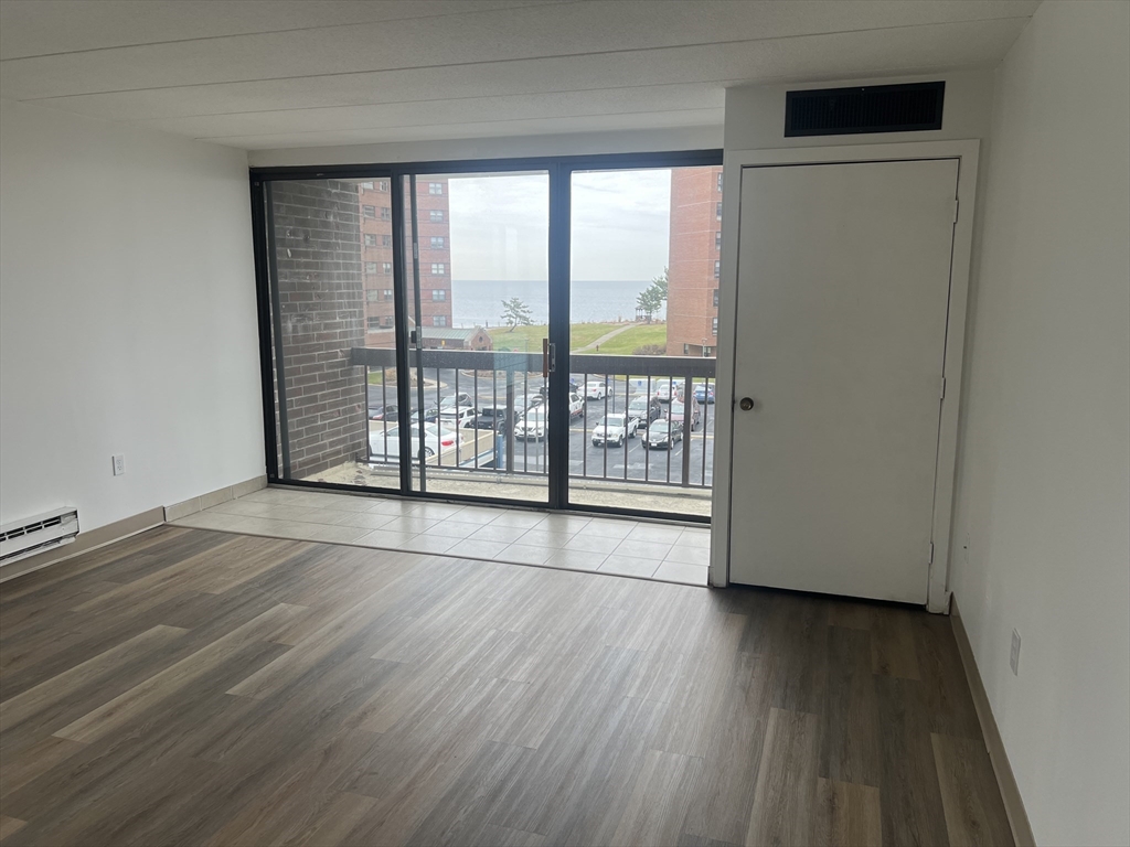 1 Pond Street, Unit 4N Winthrop, MA 02152 - Photo 3 of 13 an empty room with wooden floor and windows