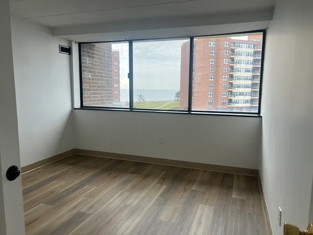 a view of an empty room with wooden floor and a window
