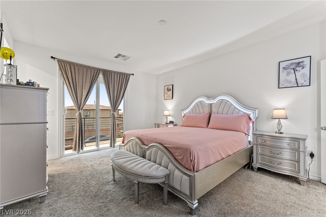 8879 Roadrunner Ravine Street Las Vegas, NV 89166 - Photo 18 of 39 Sun-filled primary bedroom features soft carpeting and a private balcony.