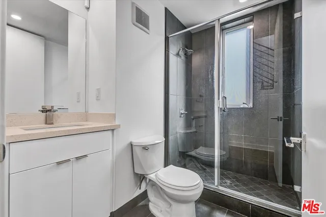 a bathroom with a shower sink vanity and toilet