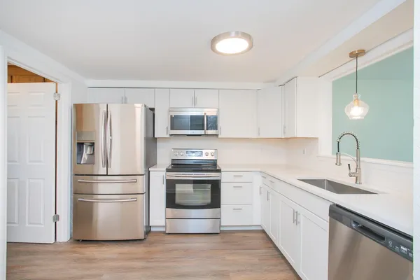 a kitchen with cabinets stainless steel appliances and wooden floor