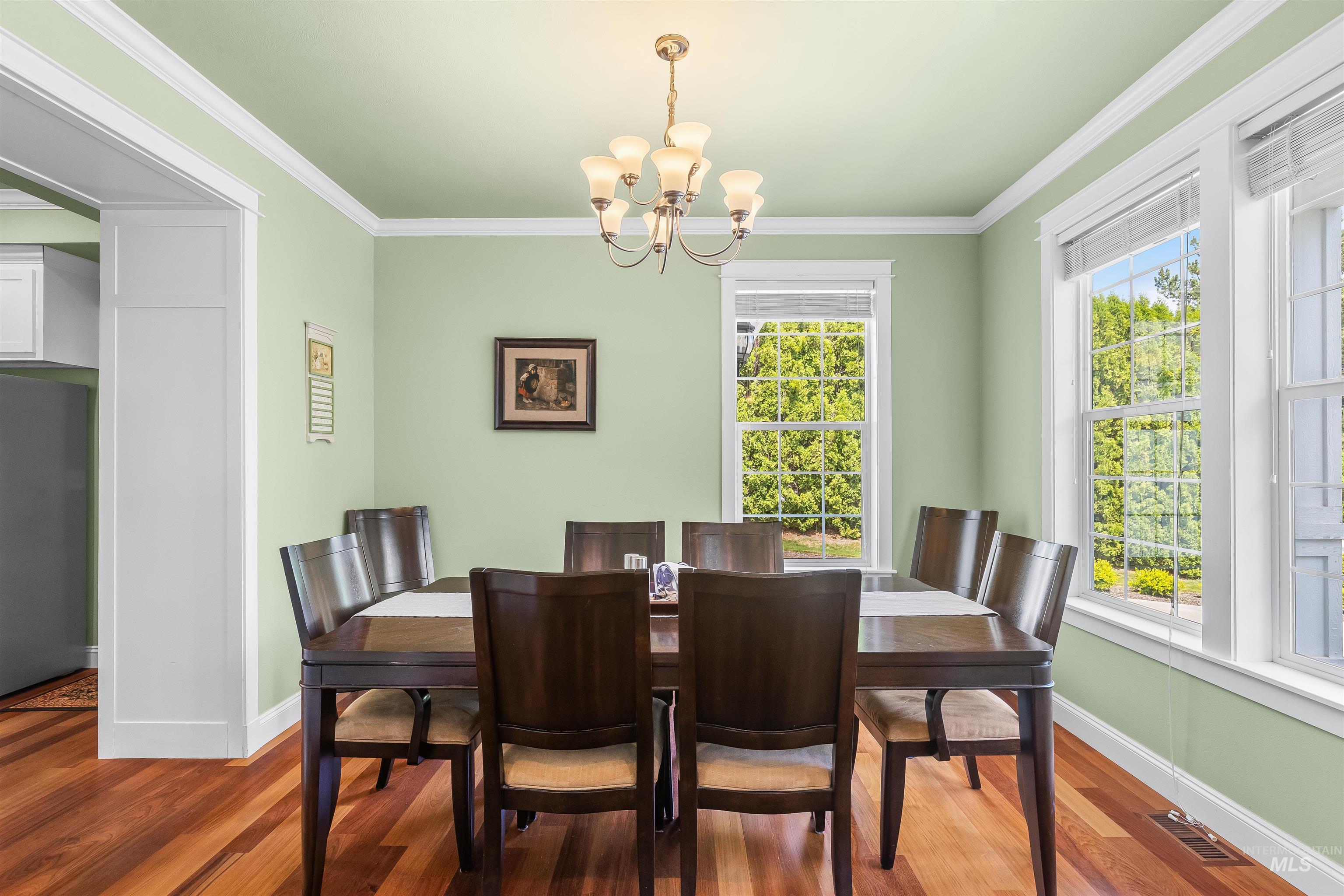 1617 Pine Cone Road Moscow, ID 83843 - Photo 7 of 44 Formal dining area featuring rich wood-finish flooring, a traditional chandelier, multiple windows, and crisp white trim details