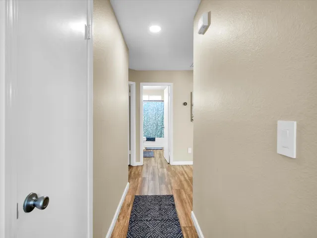a view of a hallway with wooden floor and a bathroom