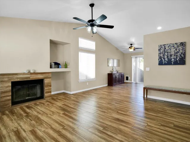 a view of a livingroom with a fireplace a ceiling fan and wooden floor