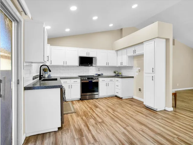 a kitchen with granite countertop a sink stove and refrigerator
