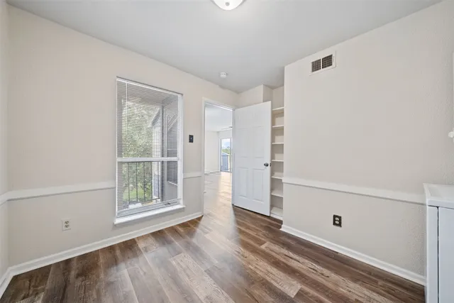 a view of empty room with wooden floor and window