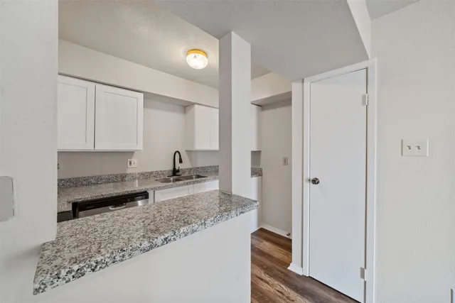 a large white kitchen with kitchen island granite countertop a sink and cabinets