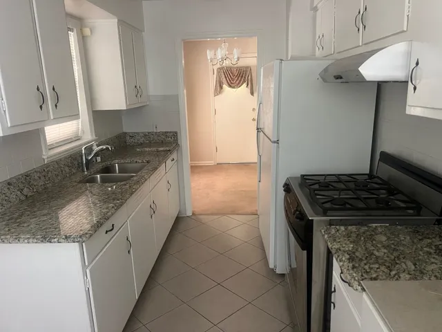 a kitchen with granite countertop stainless steel appliances a sink stove and cabinets
