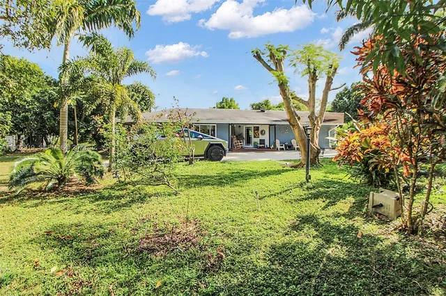 a view of a backyard with table and chairs and potted plants and large trees