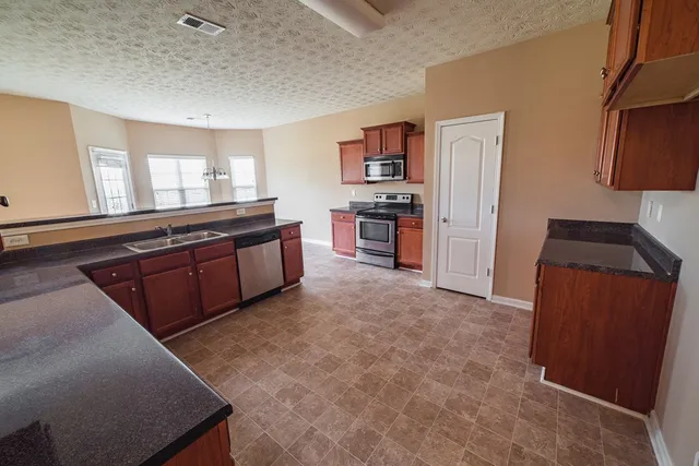 a kitchen with stainless steel appliances granite countertop a refrigerator and a stove top oven