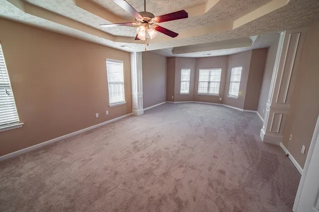 a view of a big room with windows and chandelier fan