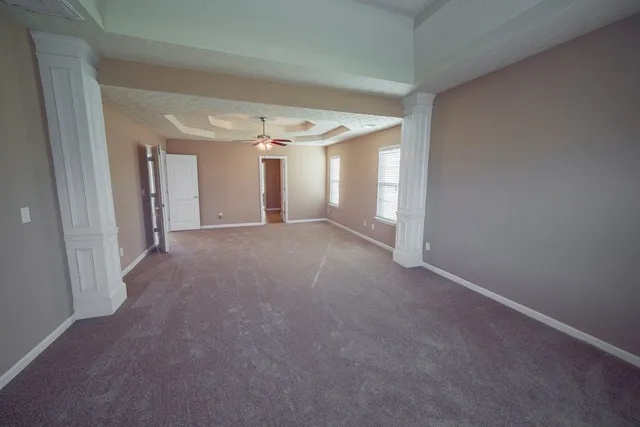 a view of a big room with windows and a ceiling fan