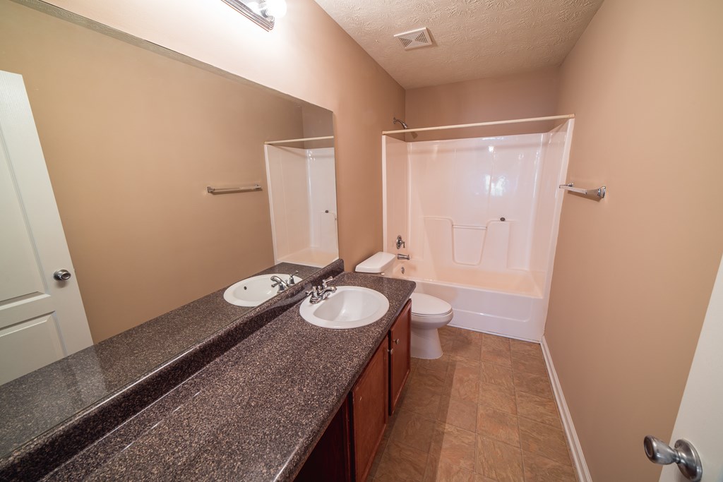 45 Apache Trail Fort Mitchell, AL 36856 - Photo 40 of 43 a bathroom with a granite countertop sink a mirror and a toilet