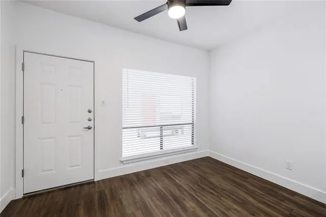 an empty room with wooden floor cabinet and windows
