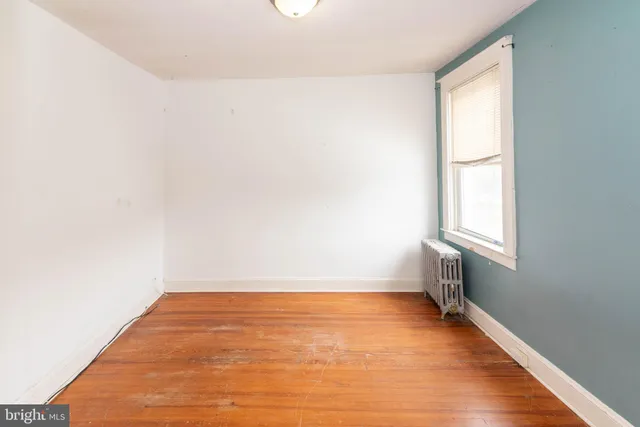 a view of an empty room with window and wooden floor
