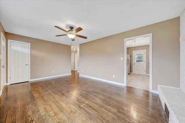 a view of an empty room with window and a kitchen