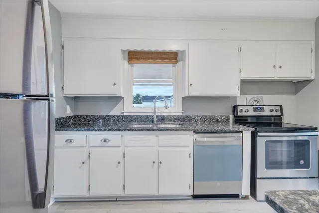 a kitchen with granite countertop white cabinets and stainless steel appliances