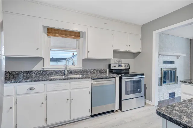 a kitchen with granite countertop a sink stove and cabinets