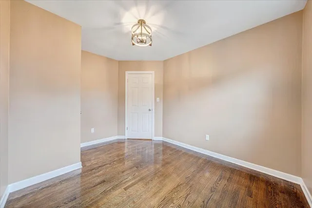 an empty room with wooden floor and chandelier