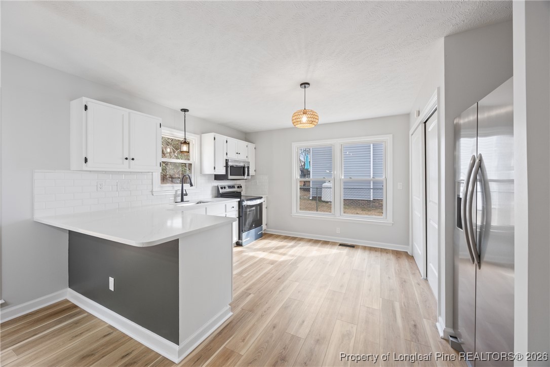 610 Duncan Road Spring Lake, NC 28390 - Photo 12 of 34 a kitchen with white cabinets and wooden floor