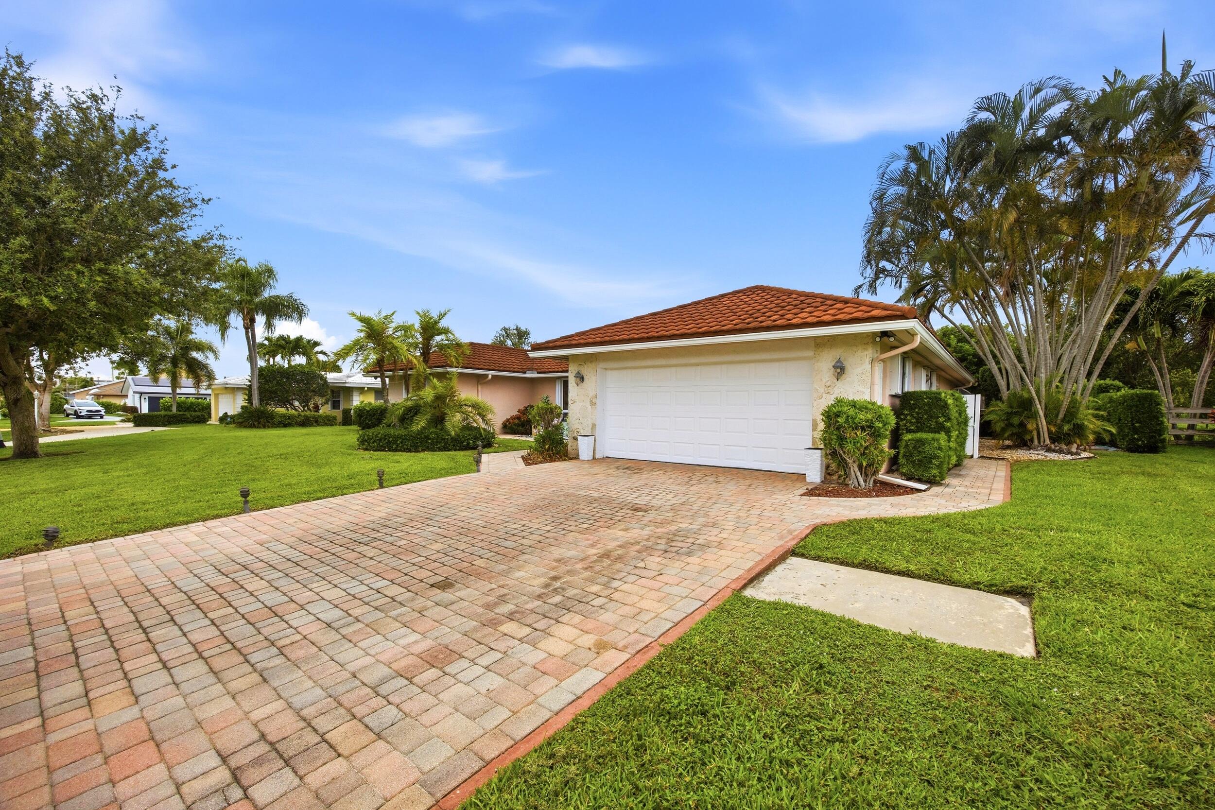 375 Northwest 53rd Street Boca Raton, FL 33487 - Photo 3 of 14 a front view of a house with a yard and garage