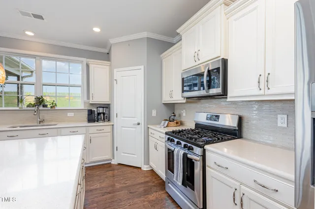 a kitchen with stainless steel appliances granite countertop a stove a sink and a microwave