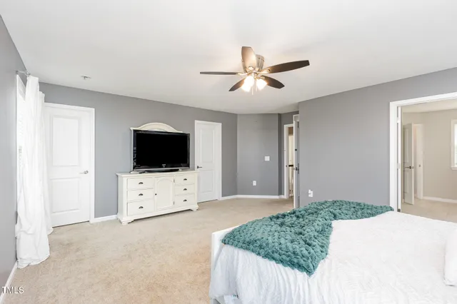 a living room with a flat screen tv on dresser and a chandelier