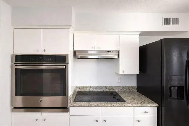 a kitchen with granite countertop white cabinets and stainless steel appliances