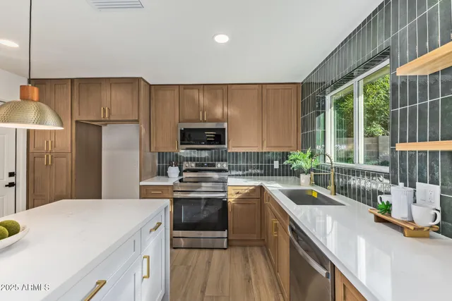 a kitchen with a sink a counter top space stainless steel appliances a large window and cabinets