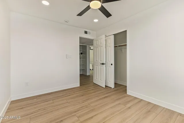 an empty room with wooden floor and ceiling fan