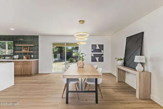 a dining room with wooden floor a chandelier a wooden table and chairs