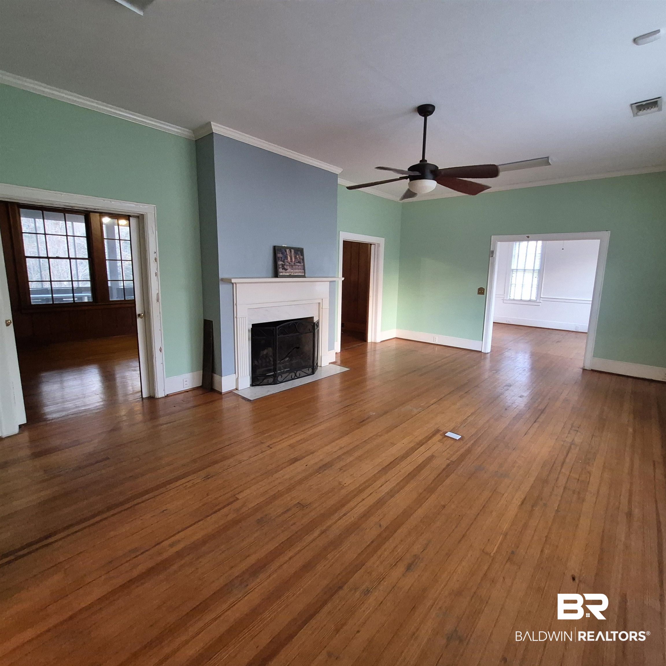 308 Rural Street Evergreen, AL 36401 - Photo 4 of 40 Unfurnished living room featuring hardwood / wood-style floors, ornamental molding, a ceiling fan, and a fireplace