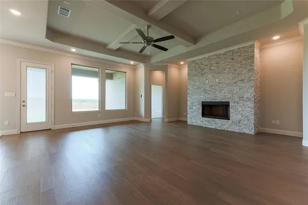 an empty room with wooden floor fireplace and windows