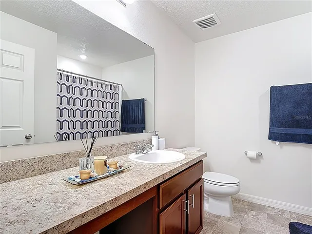 a bathroom with a granite countertop sink a toilet and a mirror