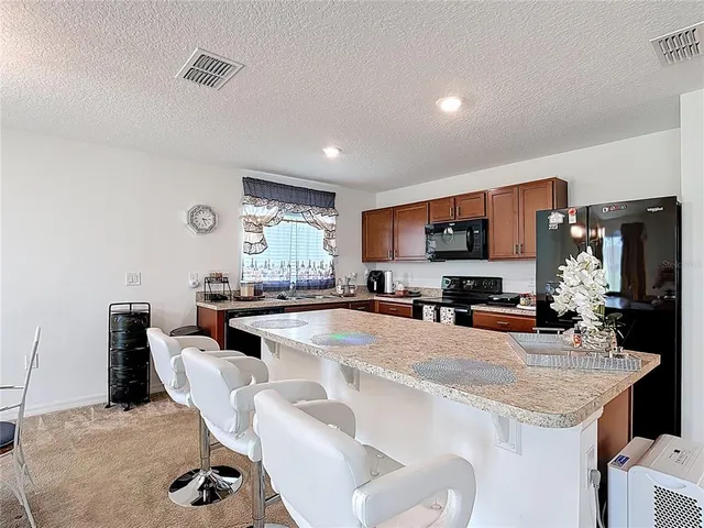 a large kitchen with granite countertop a sink counter top space appliances and cabinets