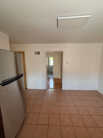 a view of a refrigerator in kitchen and an empty room