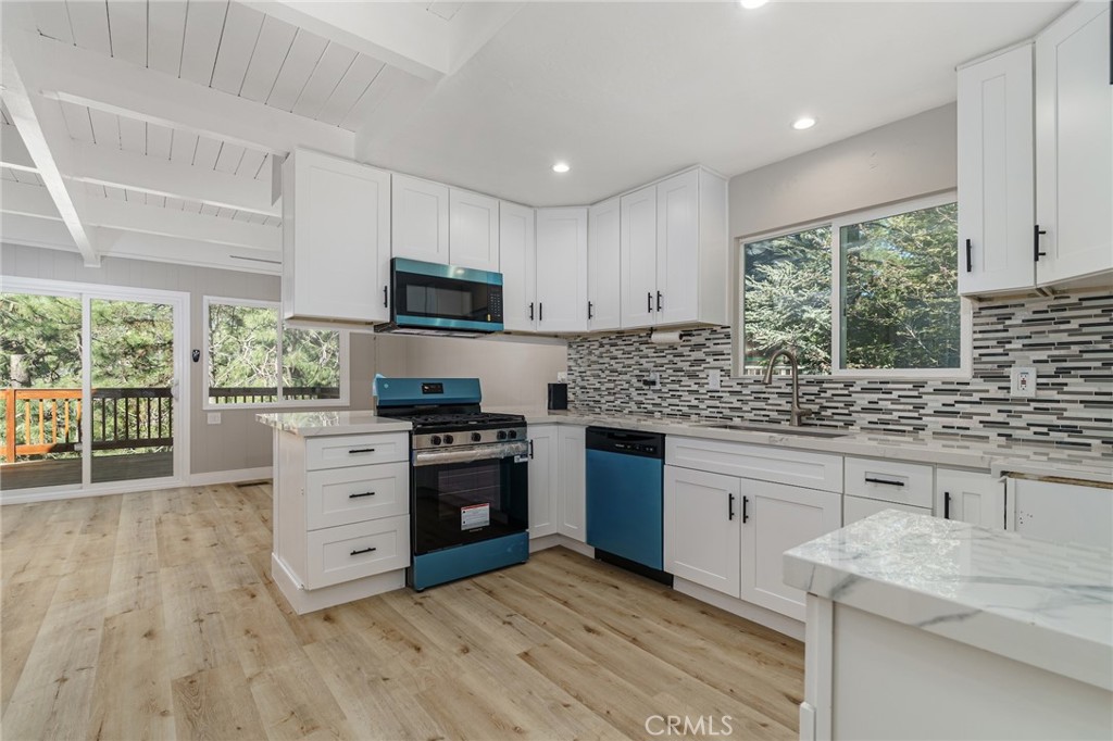 1106 Grass Valley Road Lake Arrowhead, CA 92352 - Photo 26 of 57 a kitchen with granite countertop a stove top oven a sink dishwasher a dining table and chairs with wooden floor