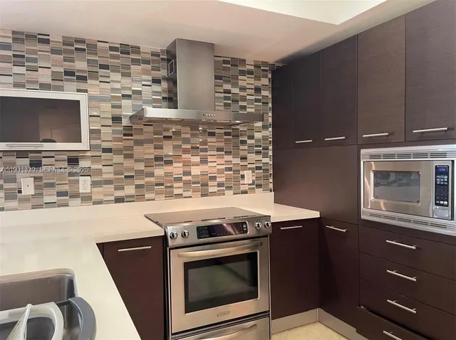 a kitchen with granite countertop a stove top oven microwave and a sink