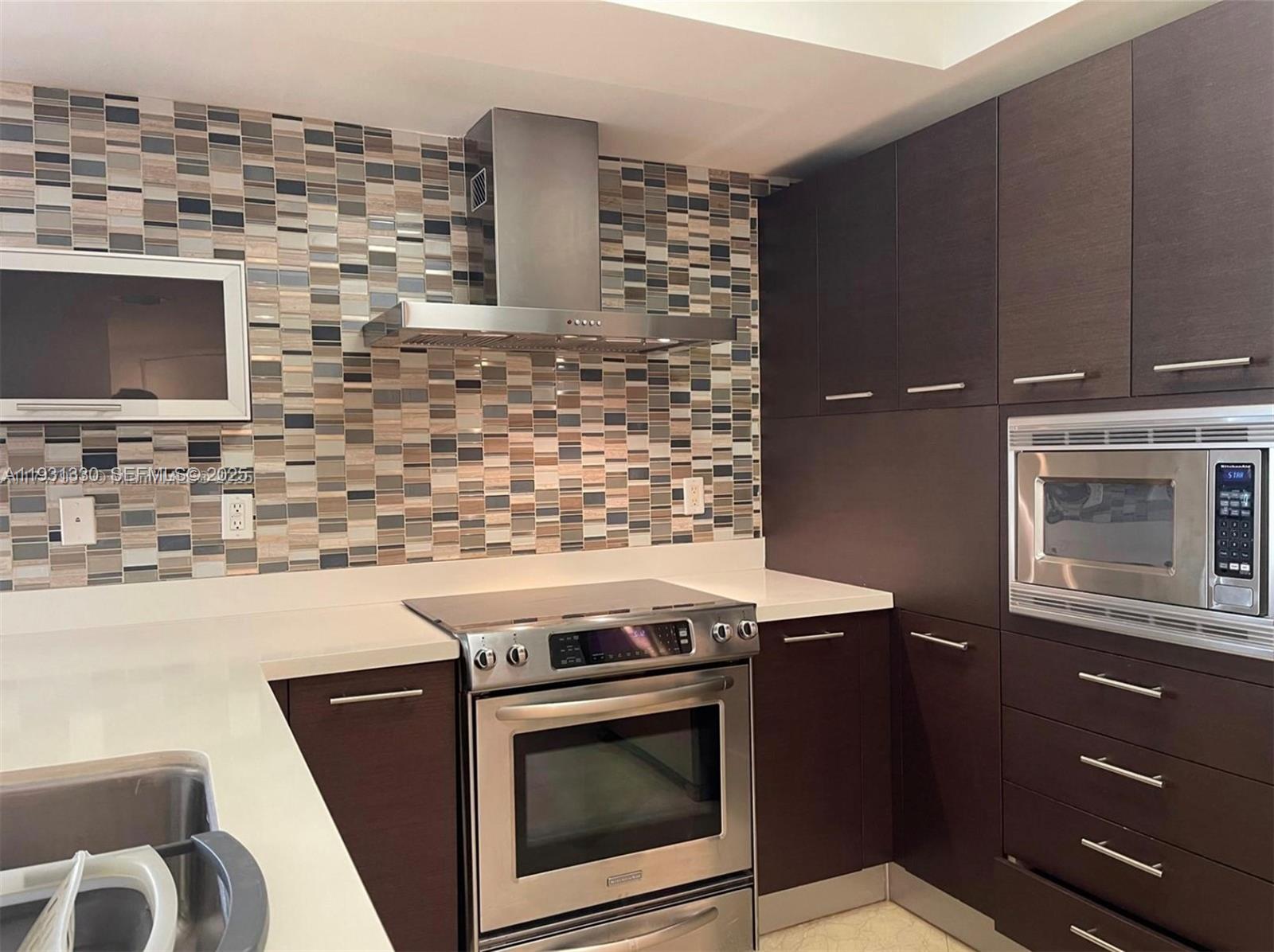 250 Sunny Isles Boulevard, Unit 31003 Sunny Isles Beach, FL 33160 - Photo 4 of 25 a kitchen with granite countertop a stove top oven microwave and a sink