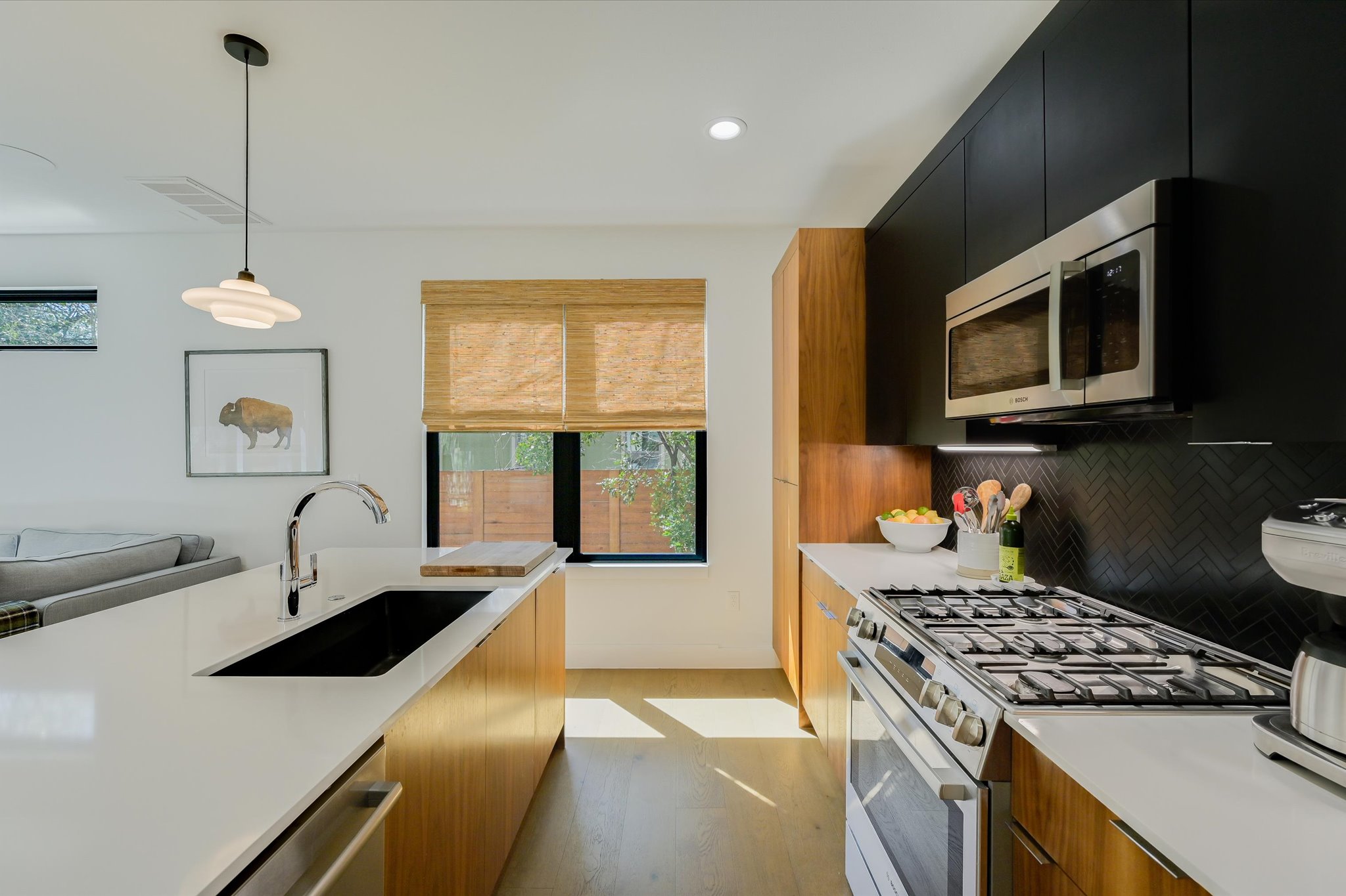 907 Redd Street, Unit 2 Austin, TX 78745 - Photo 9 of 20 Kitchen with stainless steel appliances, modern cabinets, decorative light fixtures, dark cabinetry, and light wood finished floors