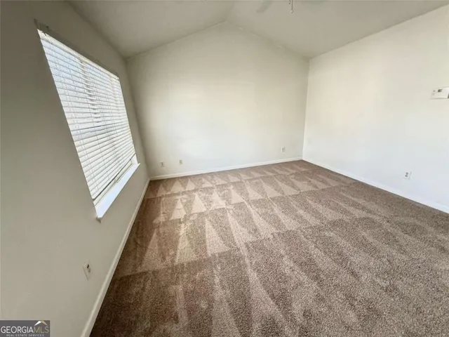 an empty room with a chandelier fan and windows