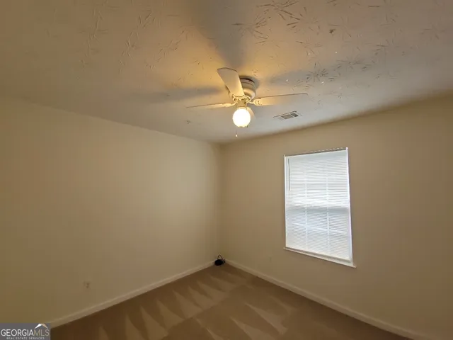 an empty room with windows and fan