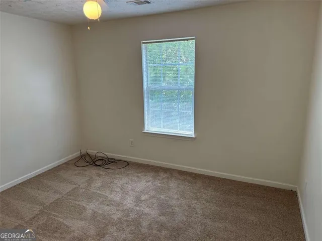 an empty room with a window and a fan