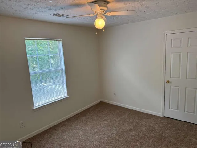 an empty room with windows and fan