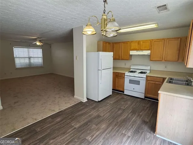 a kitchen with a sink wooden floor and stainless steel appliances