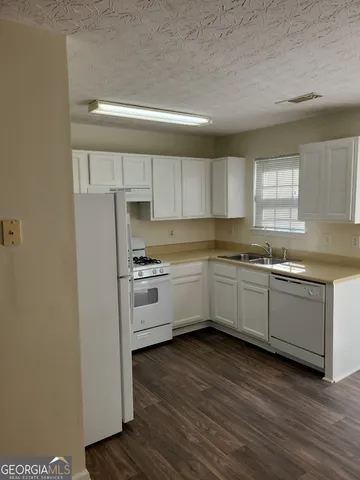 a kitchen with granite countertop white cabinets and white appliances