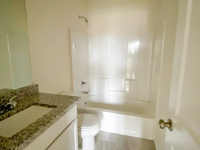 a bathroom with a granite countertop sink a toilet and bathtub