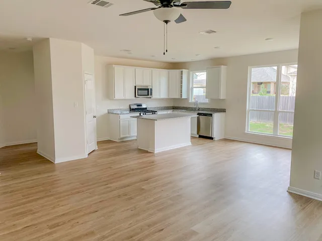 a kitchen with stainless steel appliances granite countertop a sink cabinets and wooden floor